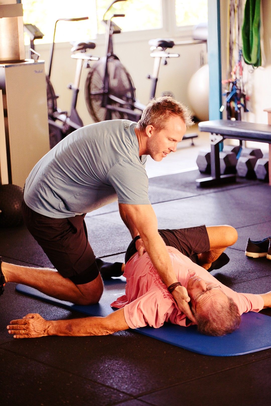 Séance de coaching solo au club Mind&Body : un coach accompagne un client sur un exercice au sol